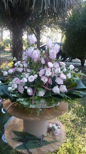 Composizione floreale di fiori rosa e bianchi in un cestino, posta all'esterno su un tavolo circolare in legno con fogliame sullo sfondo.