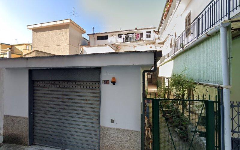 Una vista di edifici residenziali con una porta da garage in primo piano. Sono visibili anche balconi e una recinzione verde. Il cielo è limpido.